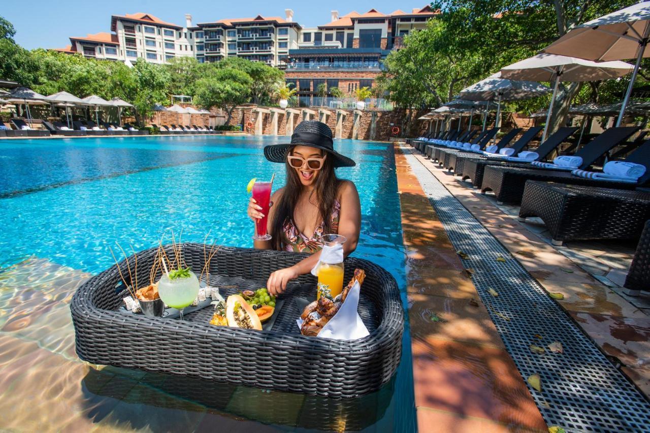 Hotel The Capital Zimbali Ballito Esterno foto A woman at a poolside lounge